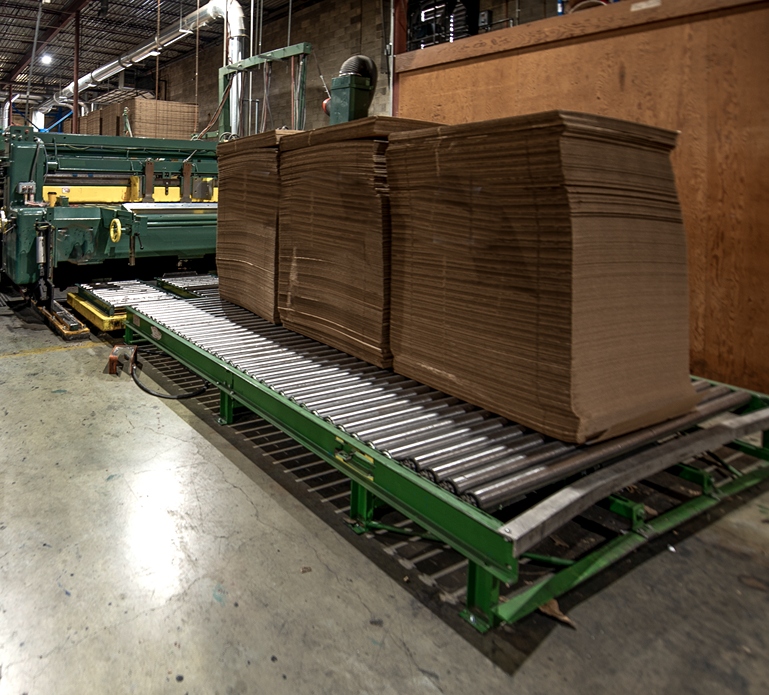 a stack of plywood moves across a roller table